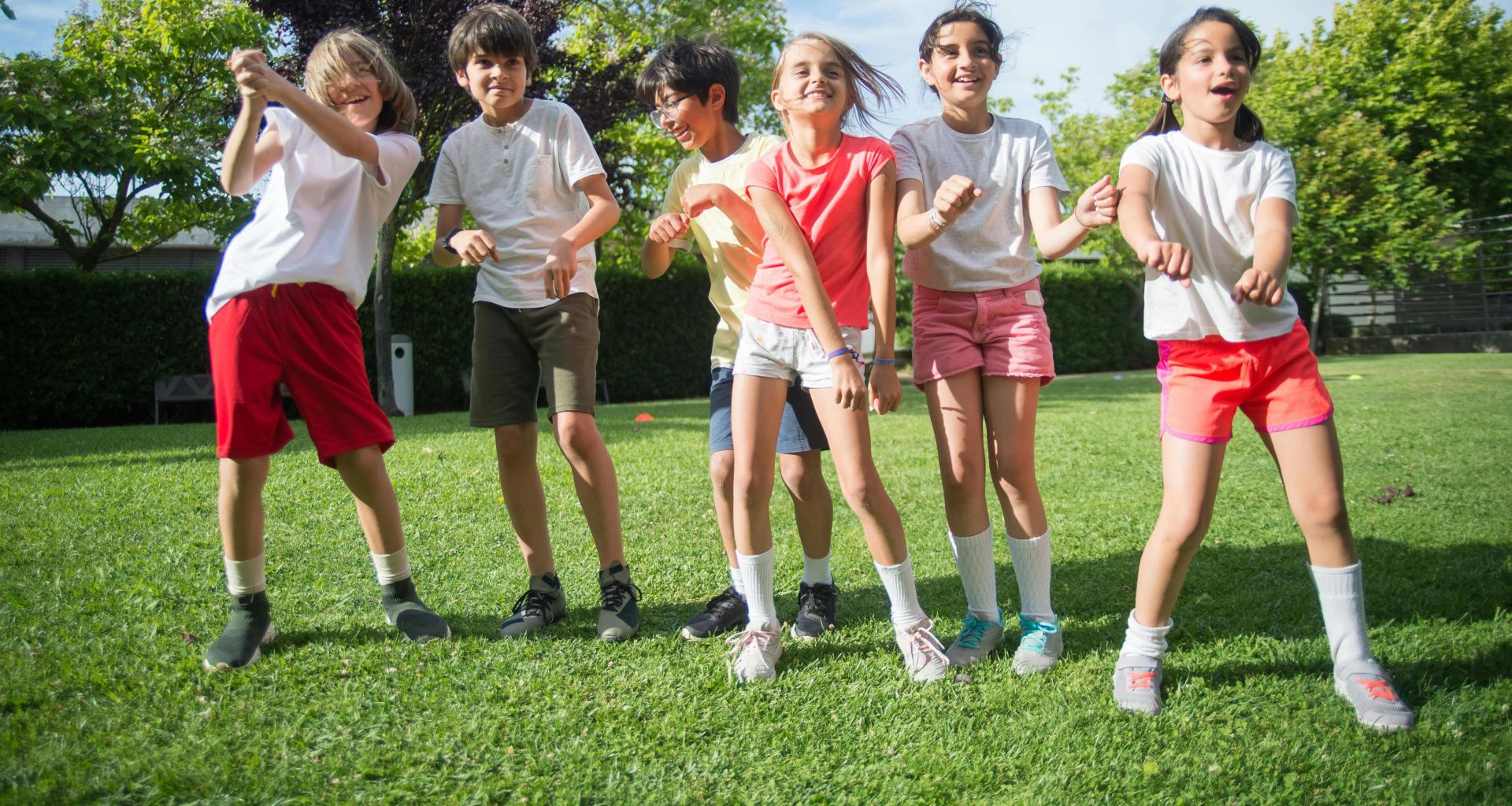 Happy group of kids playing and having fun outdoors in a green park under the sun.