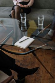 Close-up of a counseling session with two glasses of water and a notepad on a glass table.