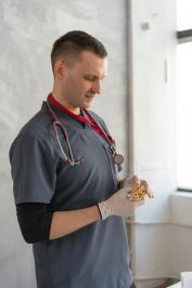 Medical professional in scrubs examining test samples in a healthcare setting.