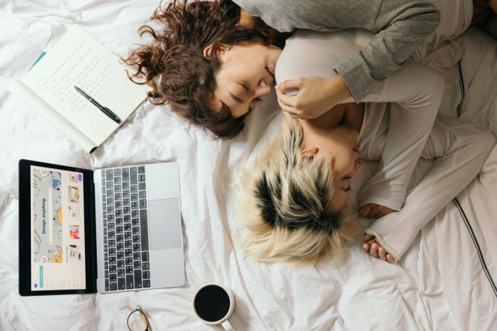 A loving couple enjoys a cozy moment with a laptop and coffee in bed, embracing tenderness and warmth.